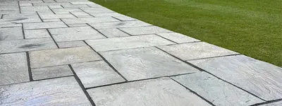 Grey sandstone paving by Hillcrest alongside a mown lawn