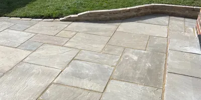 Sandstone patio laid by Hillcrest, curving round a raised lawn